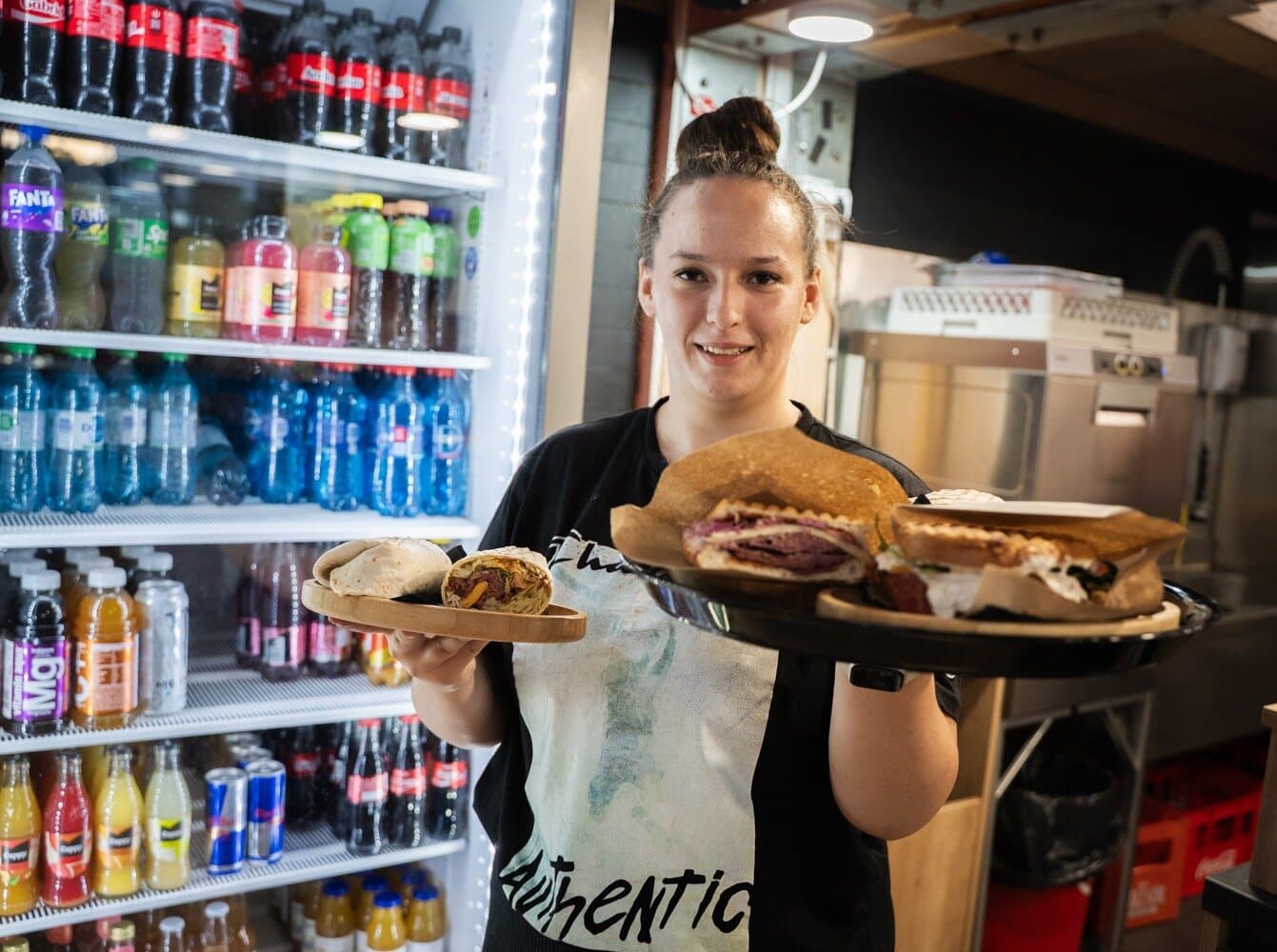 Membră a echipei Sandwich Pub aducând o tavă cu sandwich-uri proaspete